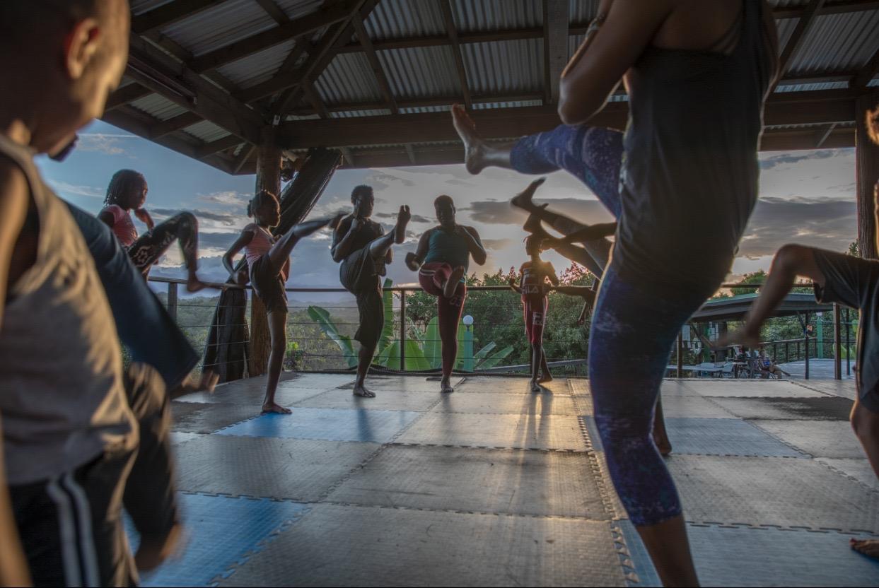 Group martial arts kicks silhouetted against sunset